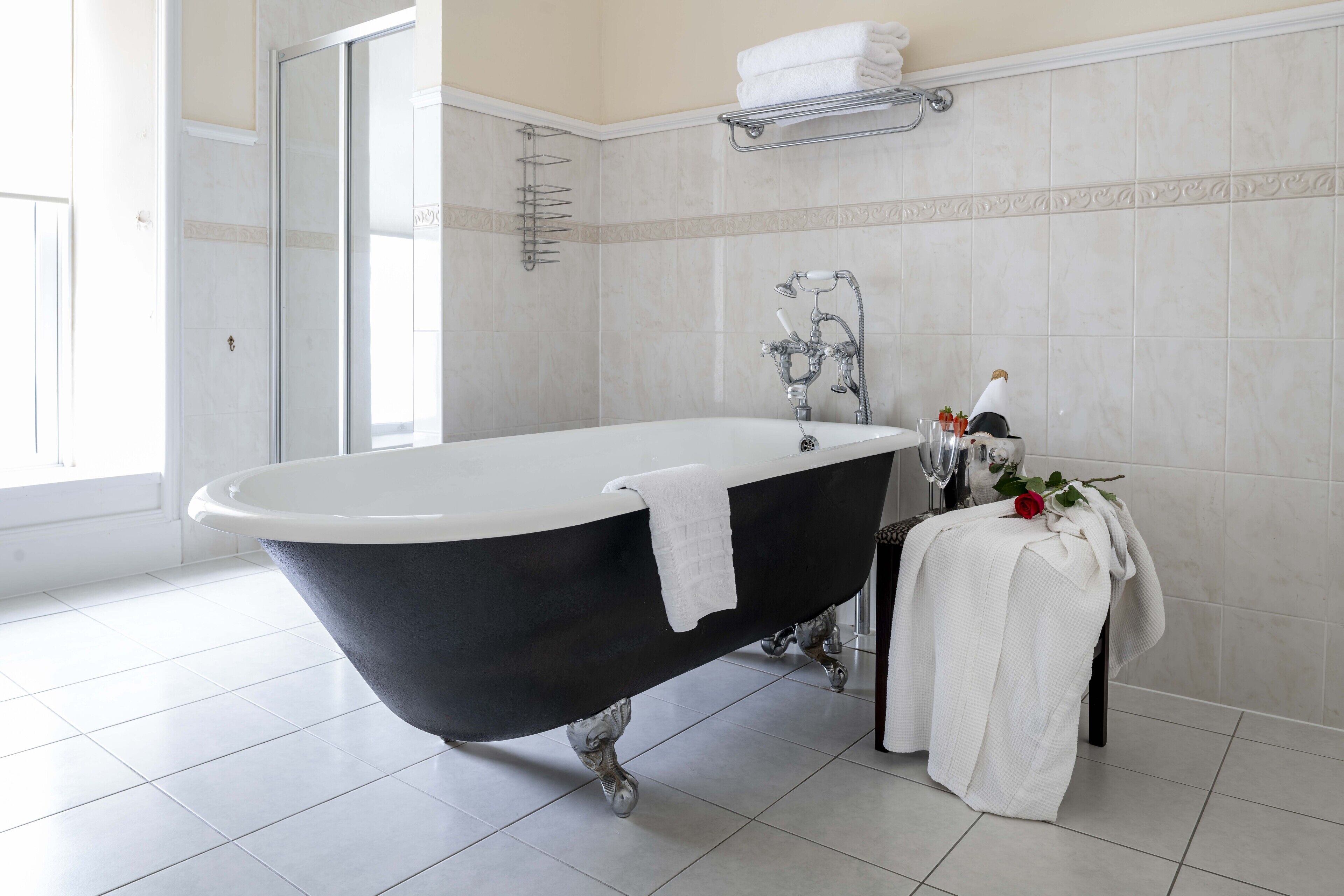A modern bathroom with a freestanding bathtub, a shower area, and a small table with toiletries.