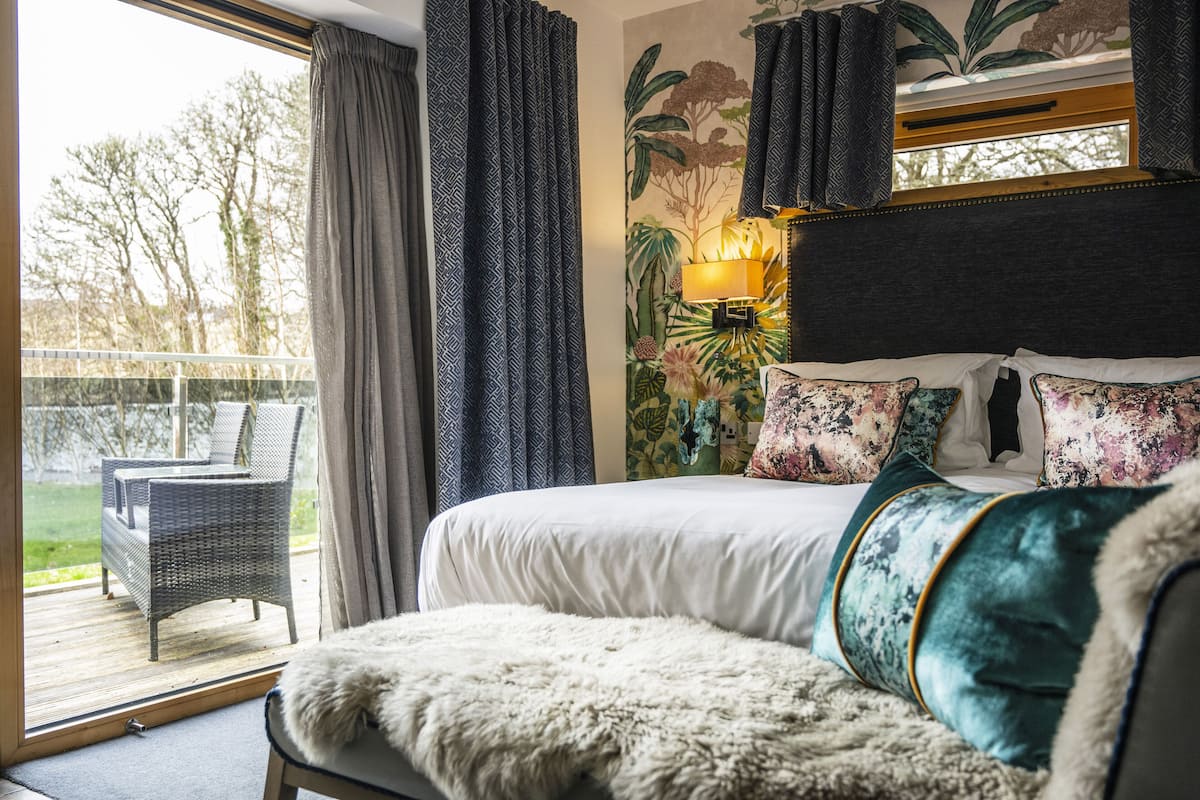 A bedroom with a large bed, a chair, and a view of the outdoors.