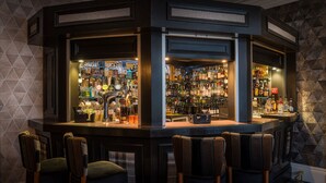 Un espace bar avec de nombreuses bouteilles d’alcool, un comptoir et des tabourets de bar.