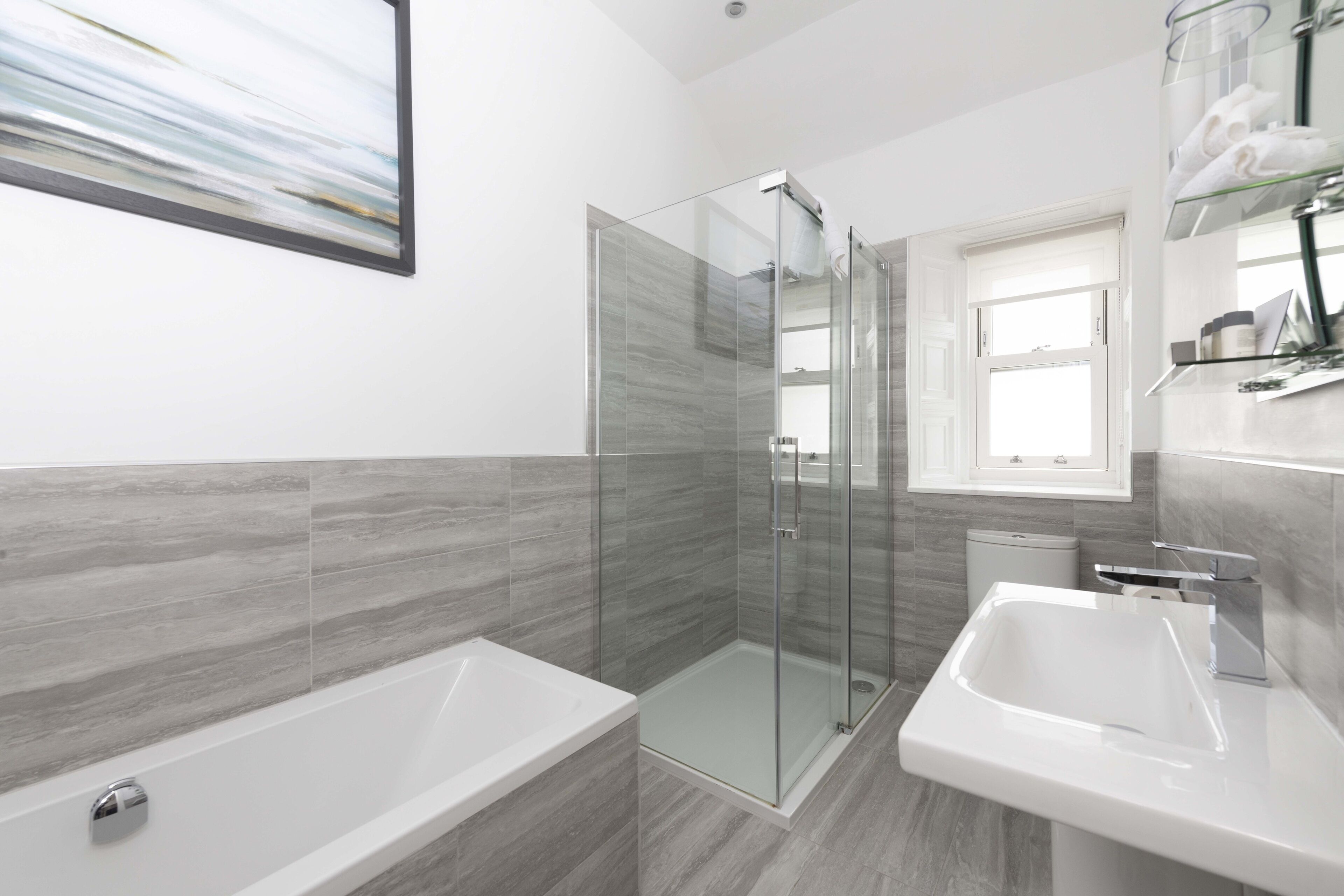A modern bathroom with a glass-enclosed shower, a bathtub, and a sink.