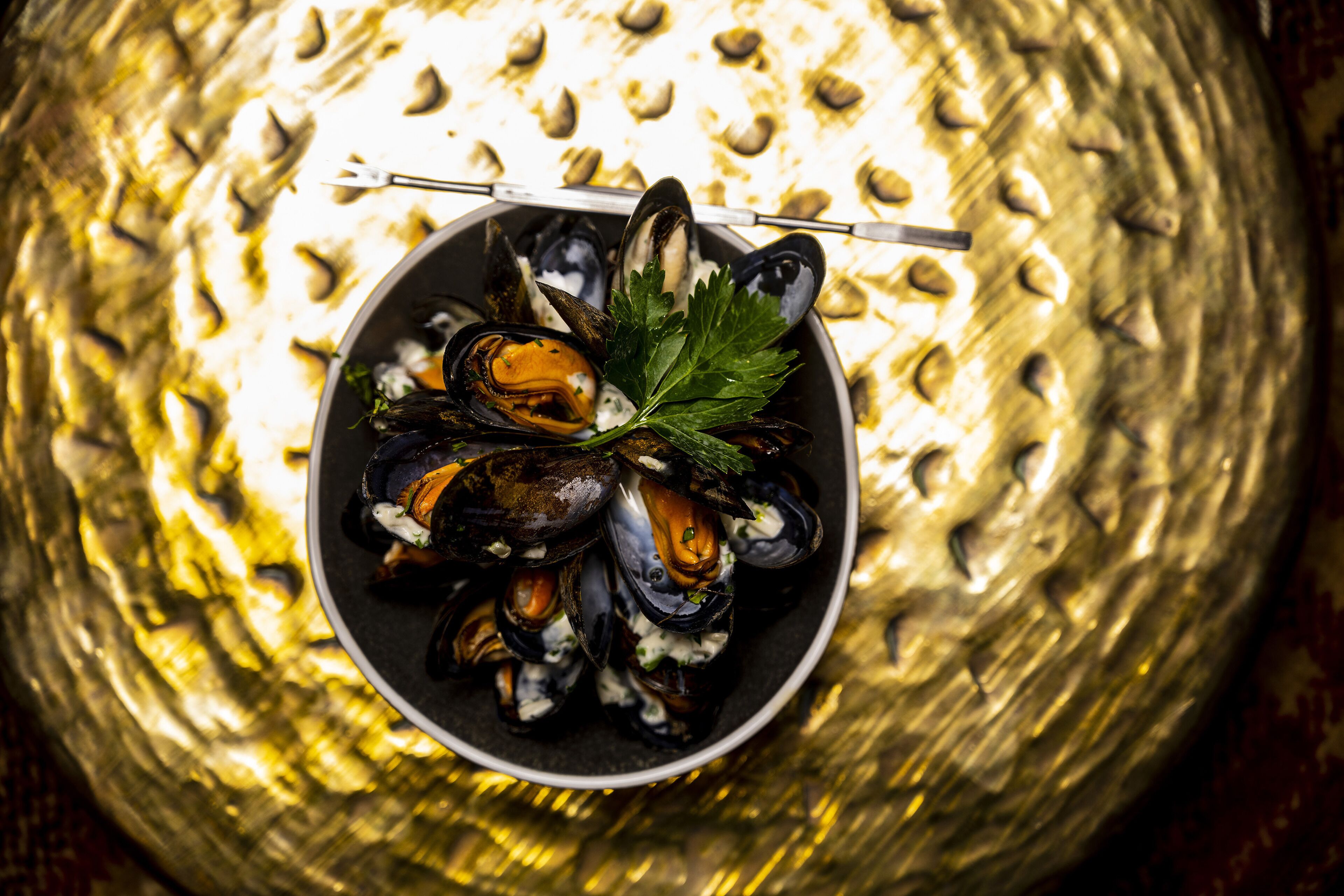 A bowl of mussels garnished with parsley.