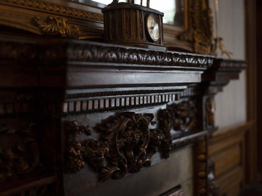 Ein detailreich gearbeiteter Holzkabinet mit aufwendigen Schnitzereien und einer Uhr obenauf.