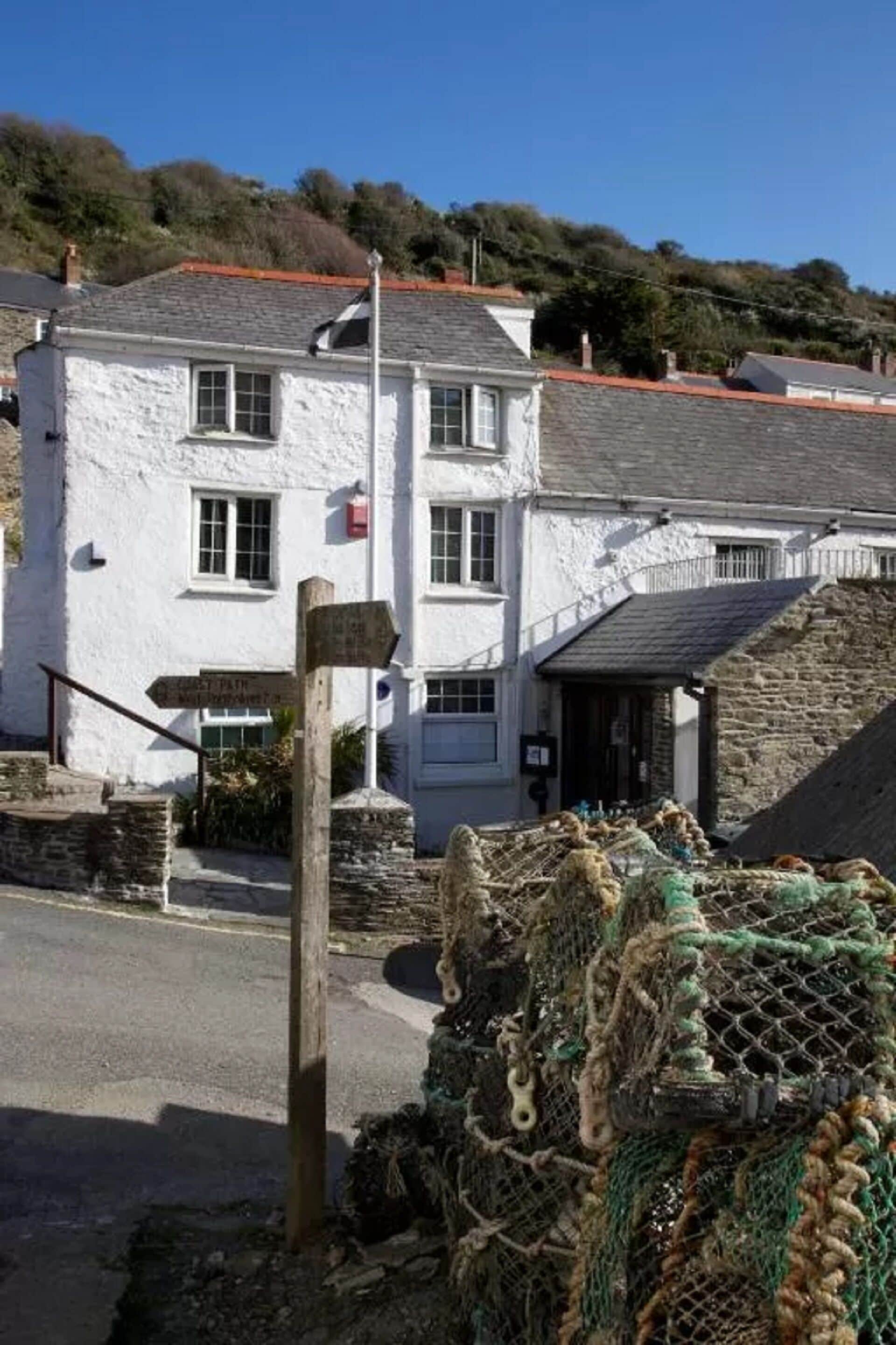 A white building with a signpost and fishing nets in front.