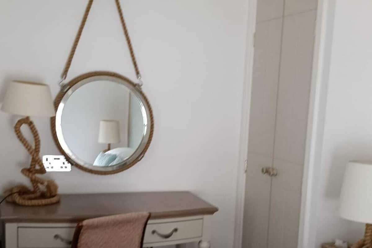 Un dormitorio con una cama, un escritorio con espejo, una silla, una lámpara y una puerta.