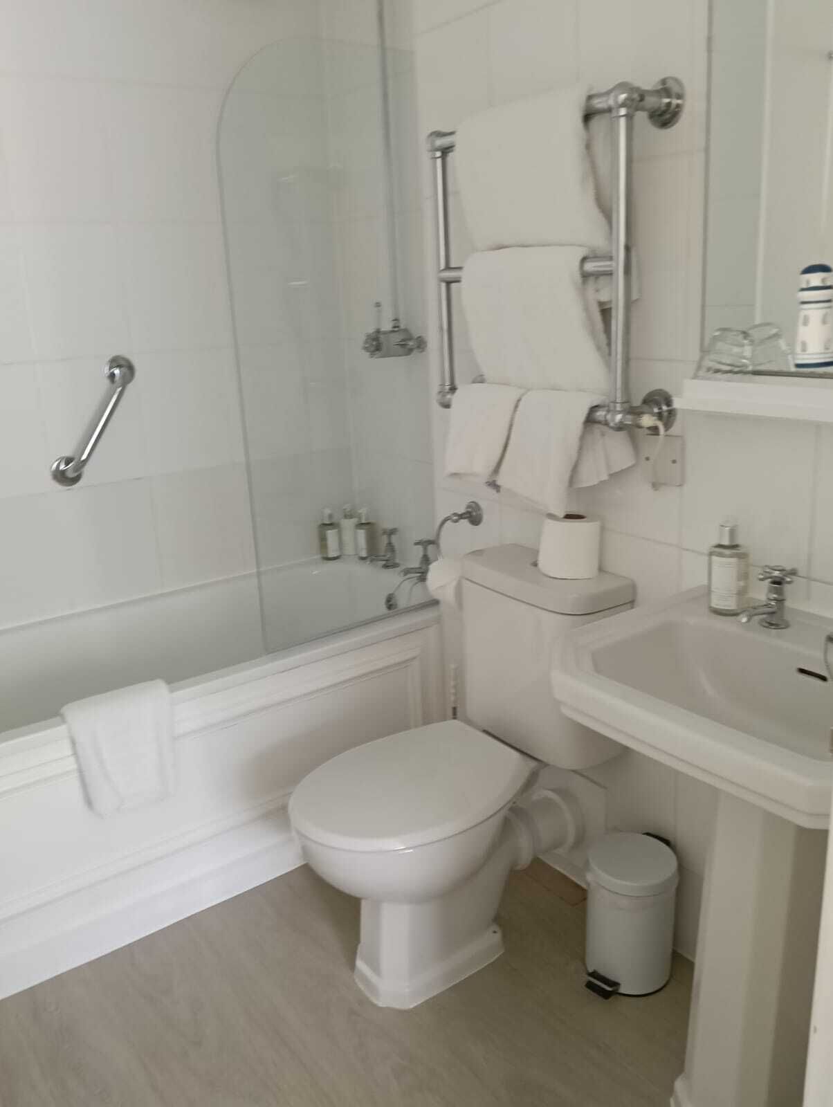 A modern bathroom with a glass-enclosed shower, a white toilet, a sink, and a trash can.