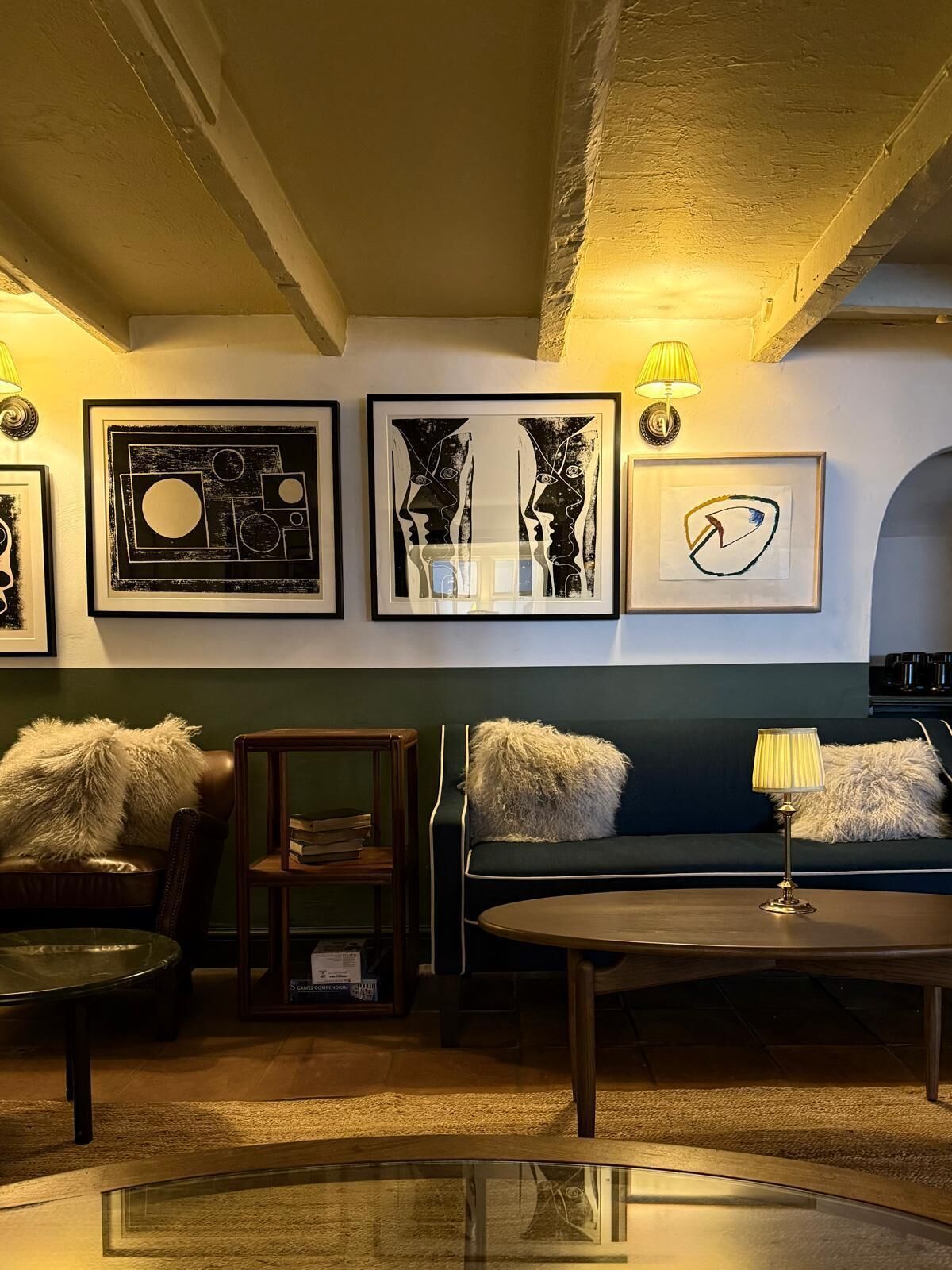 A cozy lounge area with a sofa, armchair, and coffee table, featuring artwork on the wall.