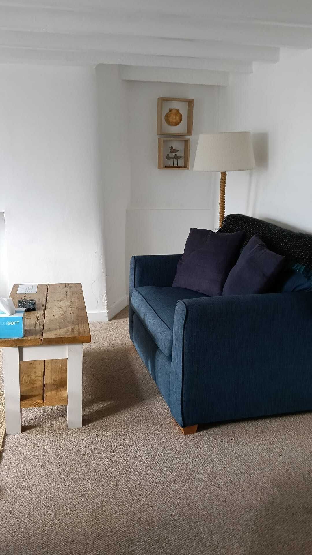 A cozy living room with a blue sofa, a wooden coffee table, and a lamp.