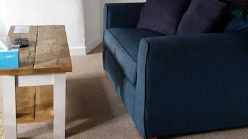 A cozy living room with a blue sofa, a wooden coffee table, and a lamp.