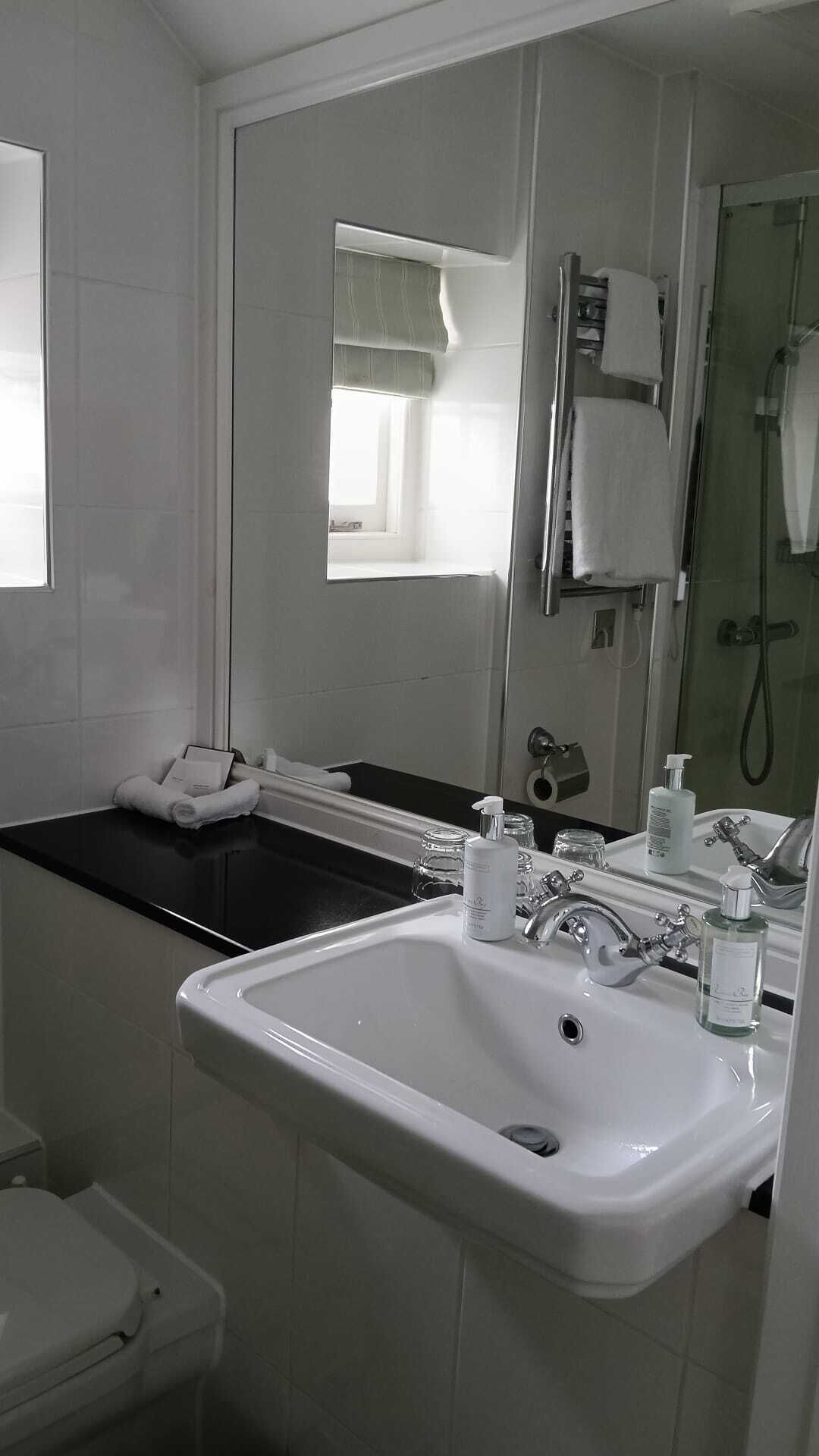 Un baño con lavamanos blanco, un espejo, una ventana con vistas, una bañera y una ducha.