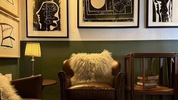 A room with a leather sofa, a round table, and framed artwork on the wall.