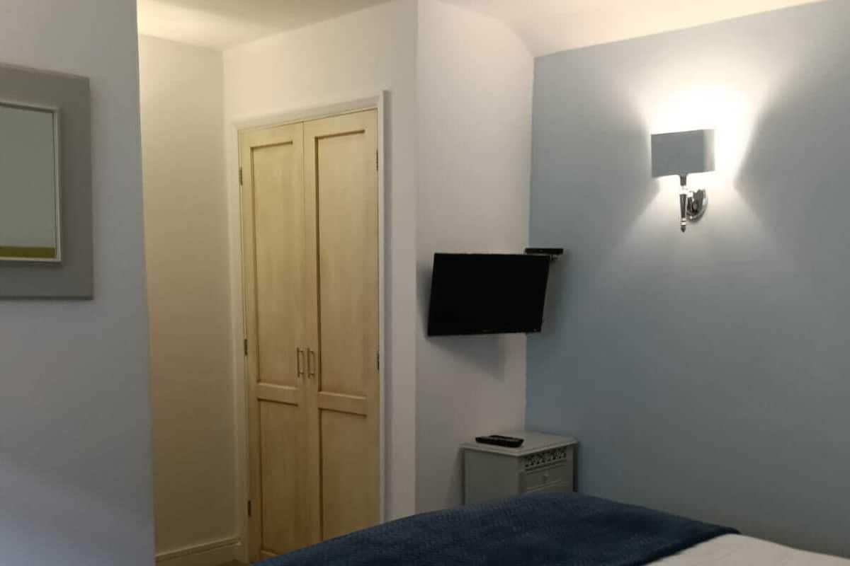 Un dormitorio con una cama, un armario, un televisor y una mesita de noche.