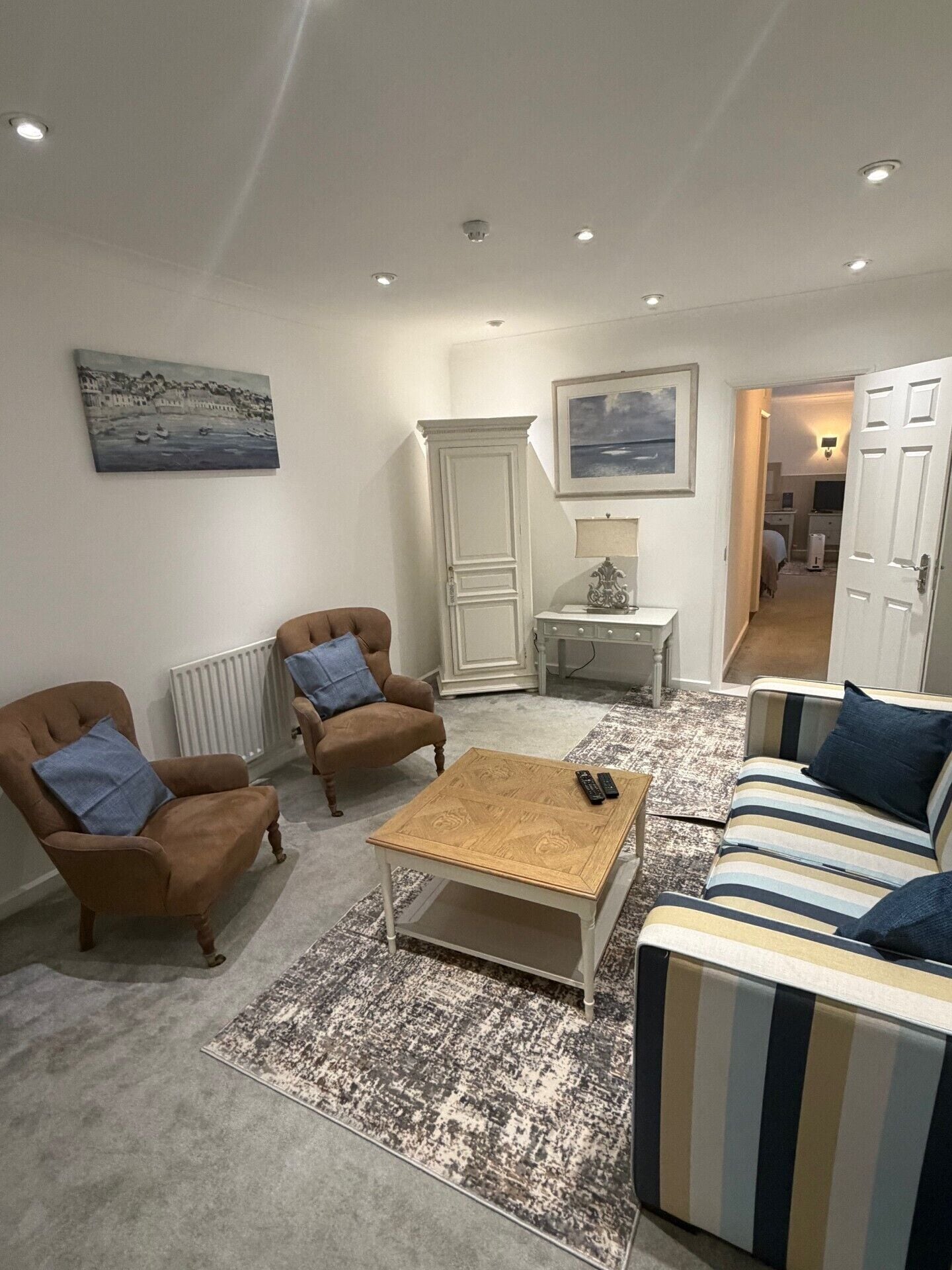 A living room with a sofa, two armchairs, a coffee table, and a cabinet.