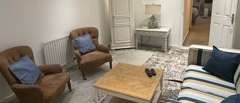 A living room with a sofa, two armchairs, a coffee table, and a cabinet.