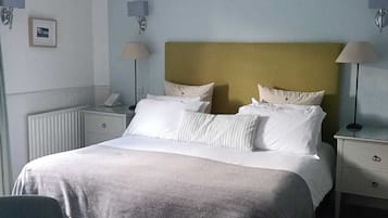 A neatly arranged hotel room with a bed, bedside tables, a chair, and a desk.