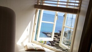 A room with a large window overlooking a rocky coastline. - The Lugger Hotel (Truro)