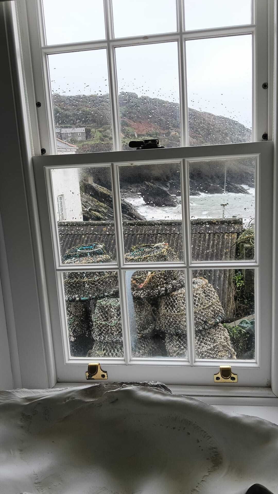 Una ventana con vista a una costa rocosa y un edificio al fondo.