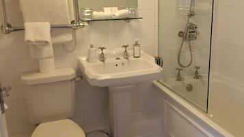 Un baño con inodoro, lavamanos y ducha con mampara de vidrio.