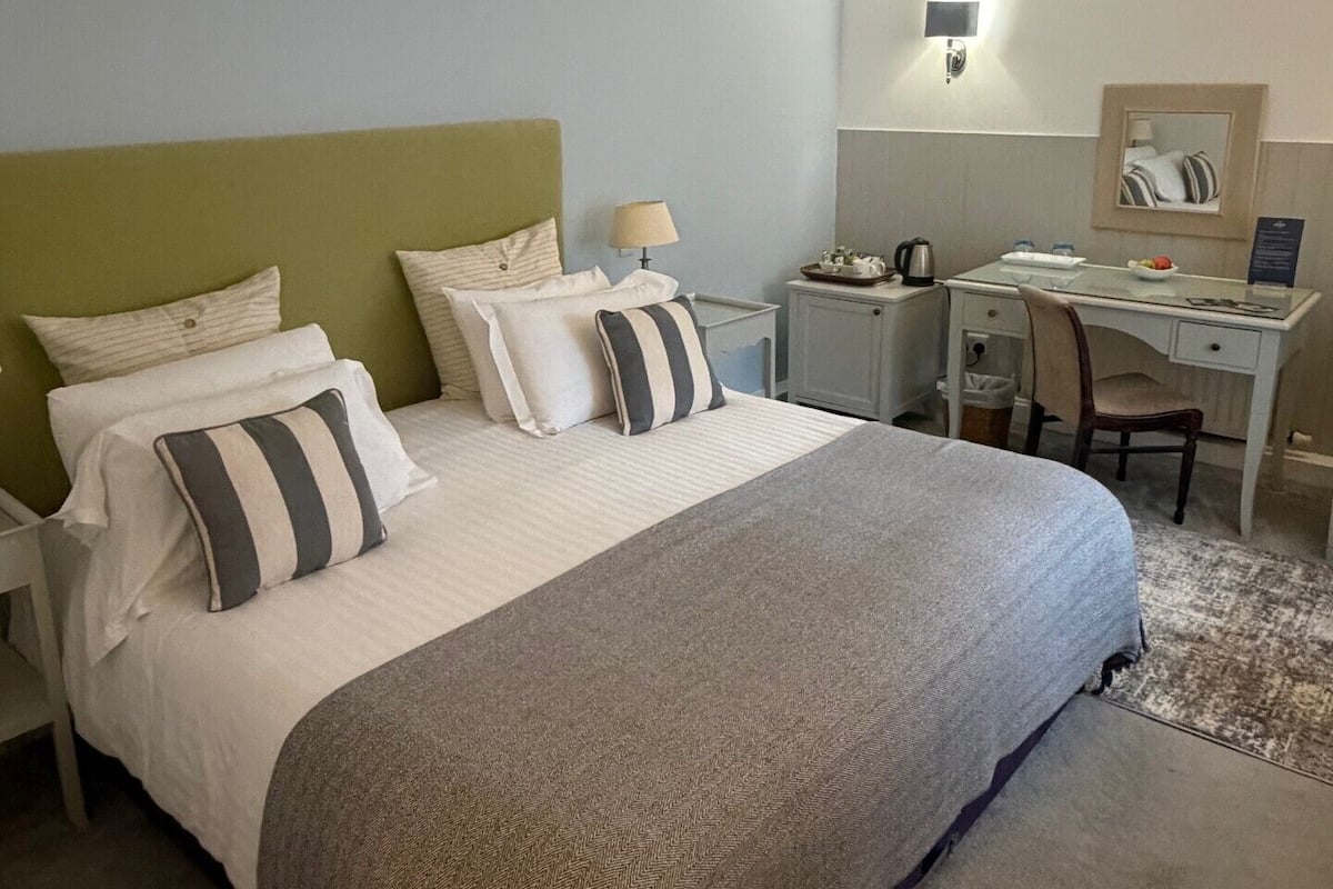 Un dormitorio ordenado con cama, escritorio y silla.