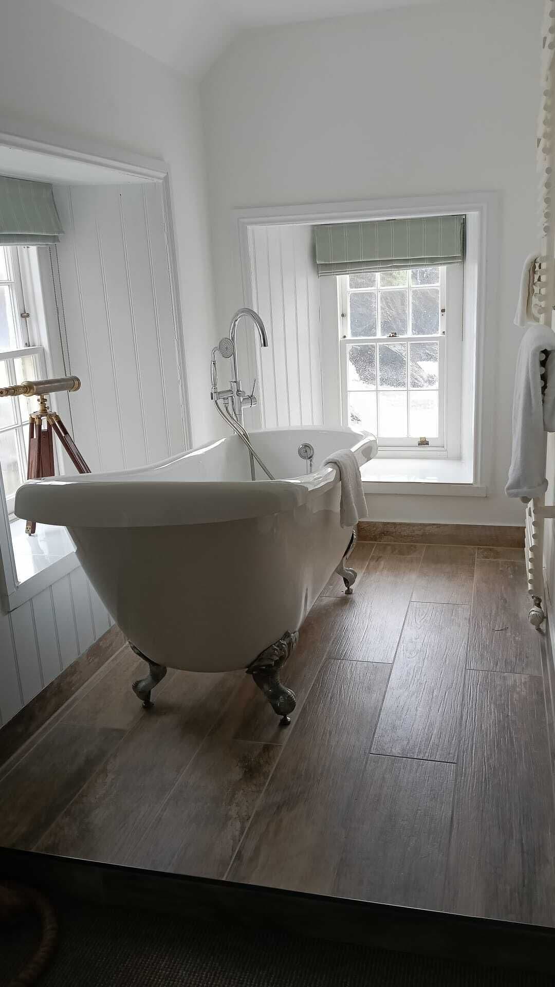 A bathroom with a freestanding bathtub, a window with a view, and a radiator.