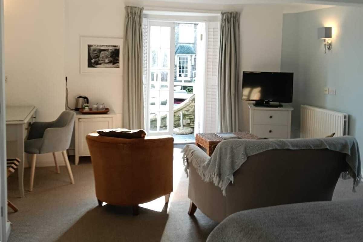 Habitación de hotel con cama, escritorio, silla, televisión y vista a un edificio a través de una ventana.