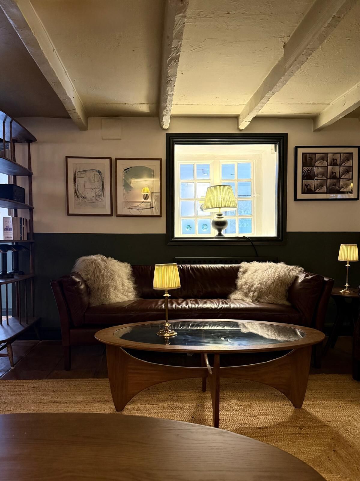 Une pièce chaleureuse avec un canapé en cuir, une table basse ronde et une bibliothèque.