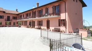 A pink building with a balcony, potted plants, and outdoor seating. - Al Brich (Albaretto della Torre)