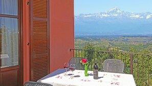A balcony with a table set for two, a bottle of wine, and a vase with a flower. - Al Brich (Albaretto della Torre)