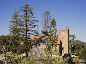A church with a clock tower, surrounded by trees and a clear sky.