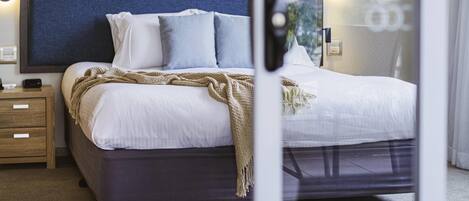A neatly arranged hotel room with a bed, bedside tables, and a view through a window.
