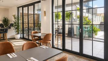 A modern dining area with large windows, a brick wall, and a mix of seating arrangements.