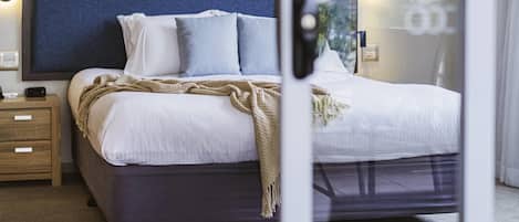 Une chambre d’hôtel bien aménagée, avec un lit, des tables de chevet et une vue par la fenêtre.