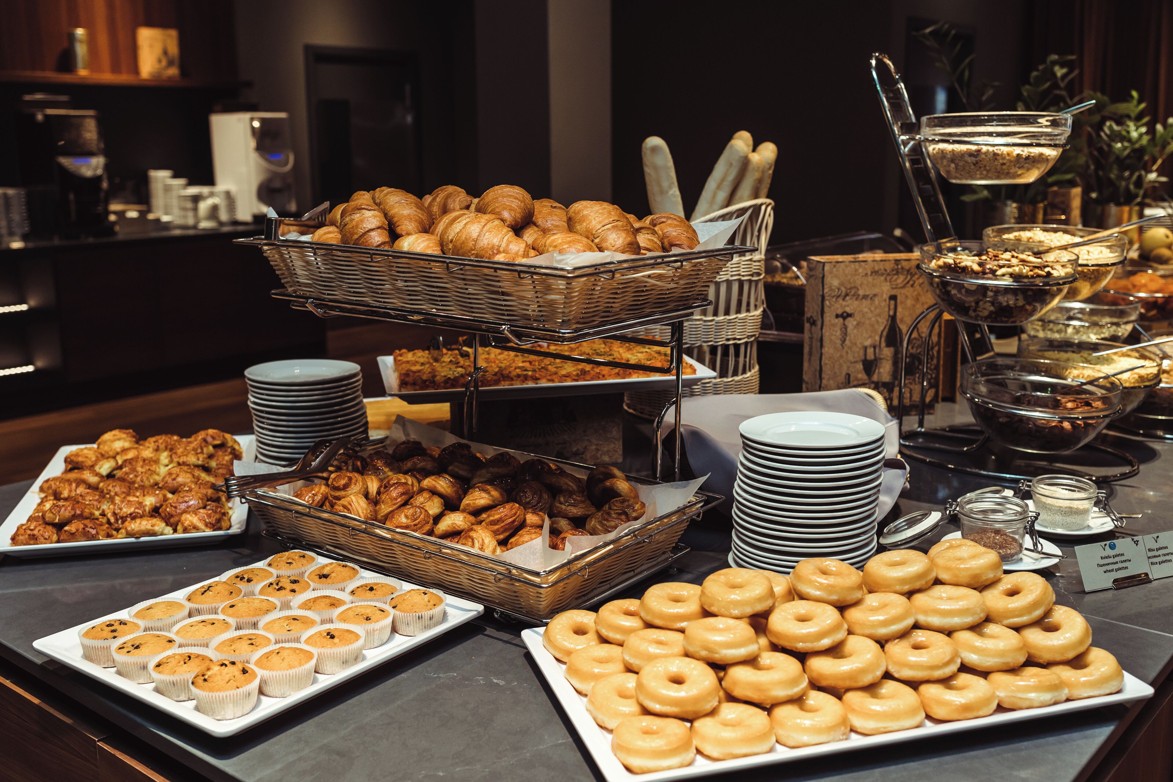A buffet with various pastries and baked goods, including croissants, muffins, and donuts.