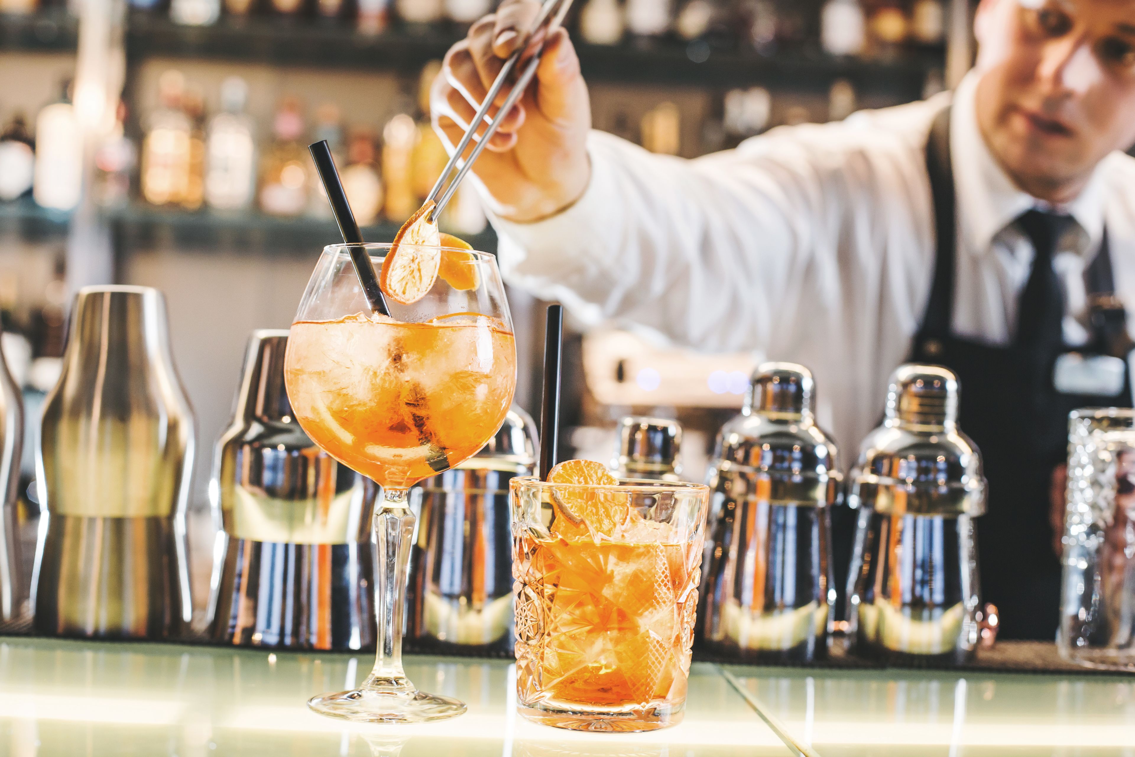 En bartender laver en cocktail med en shaker og et glas på bardisken.