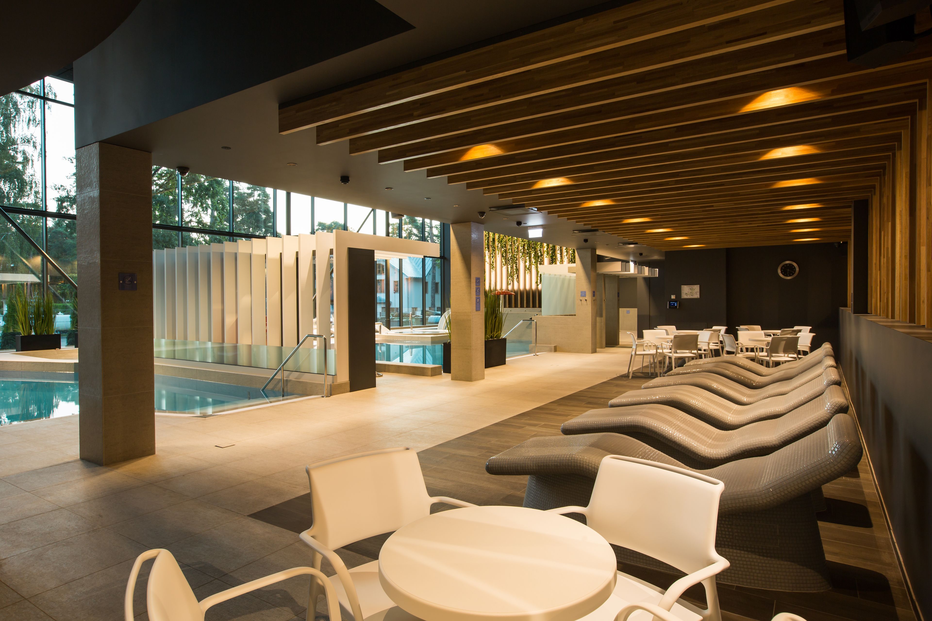 A modern indoor pool area with lounge seating and a view of the pool.