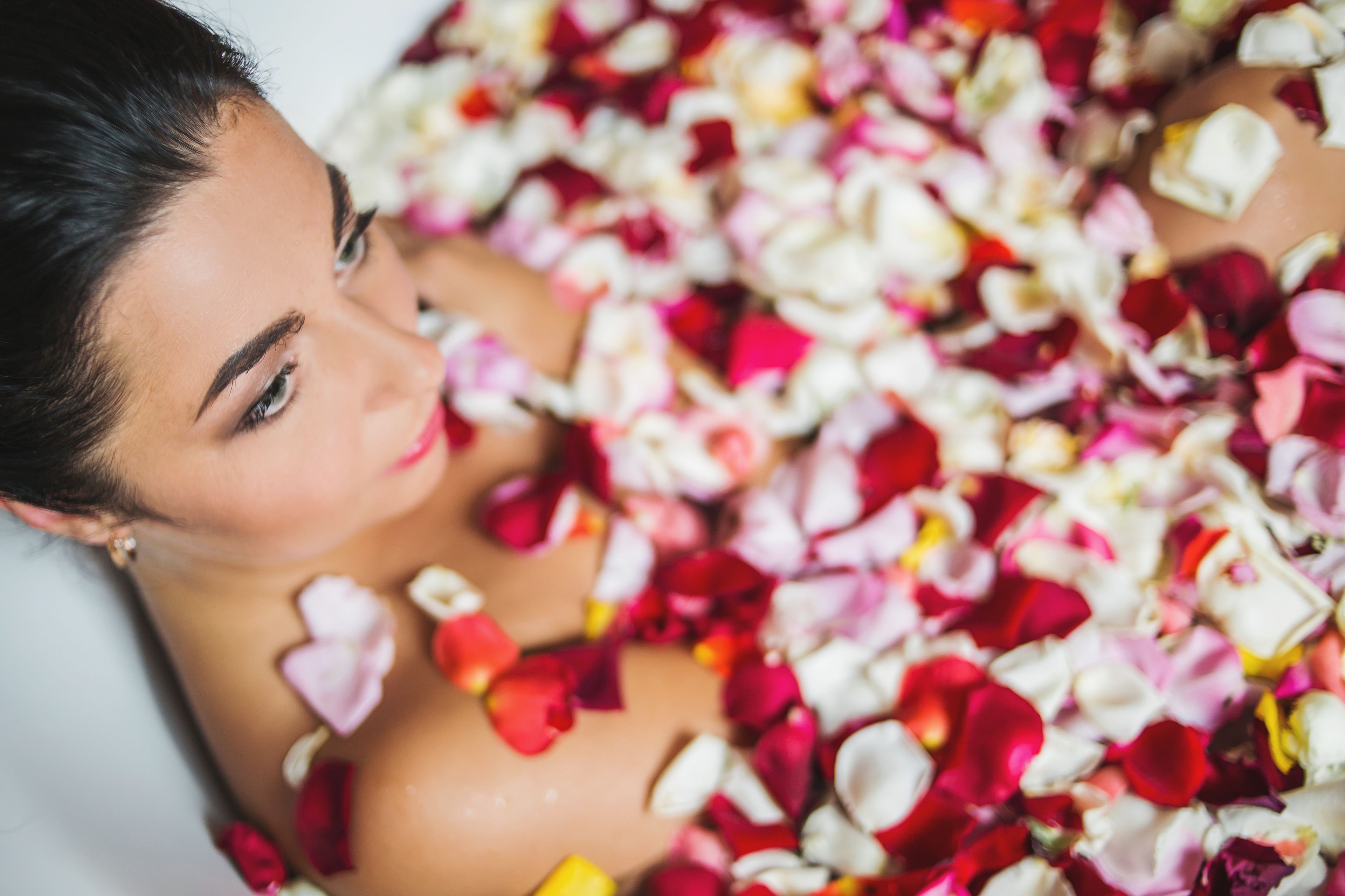 Une personne allongée, entourée de pétales de rose.