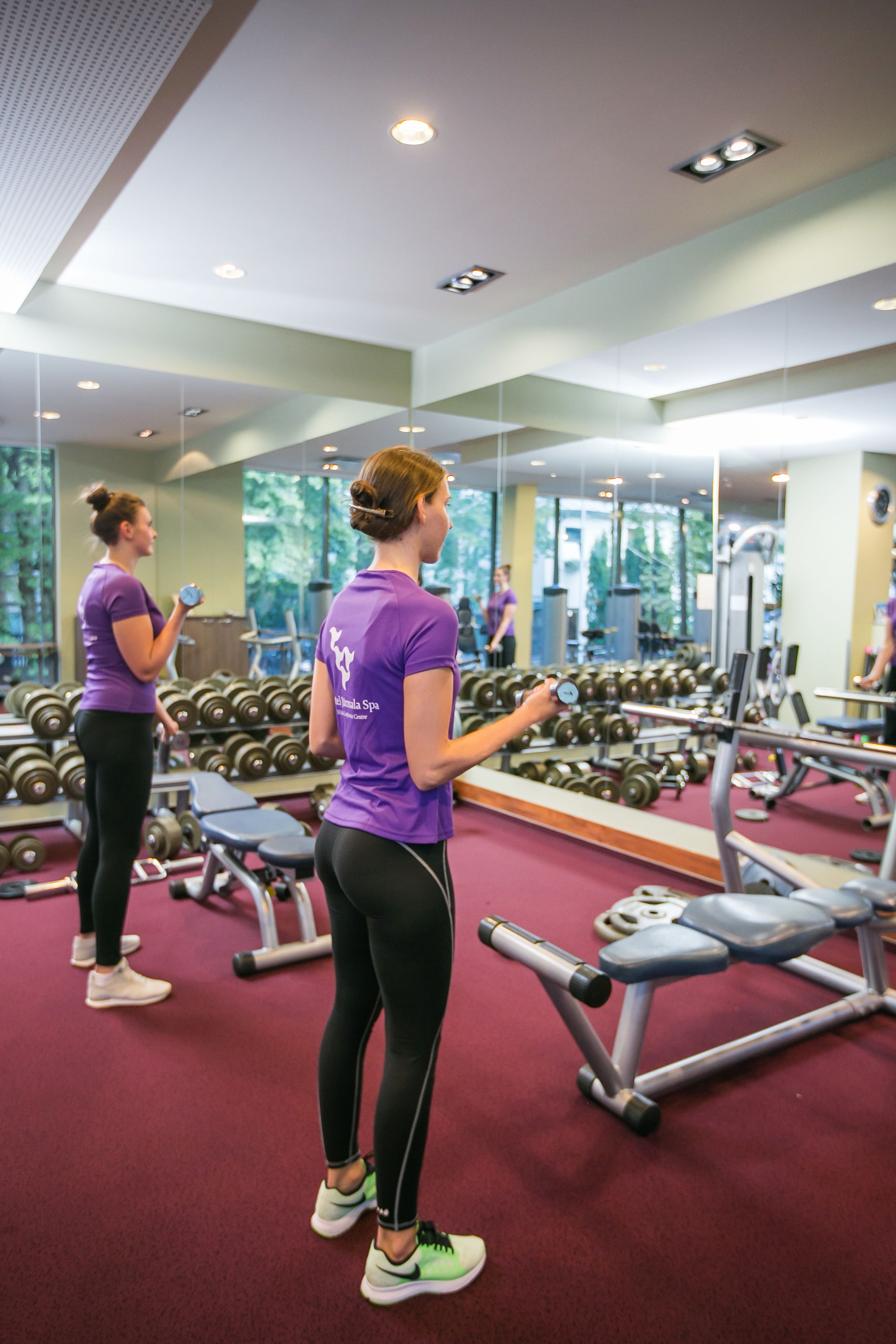 A gym with exercise equipment and mirrors.
