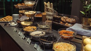 A buffet with various food items and a plant in the corner.