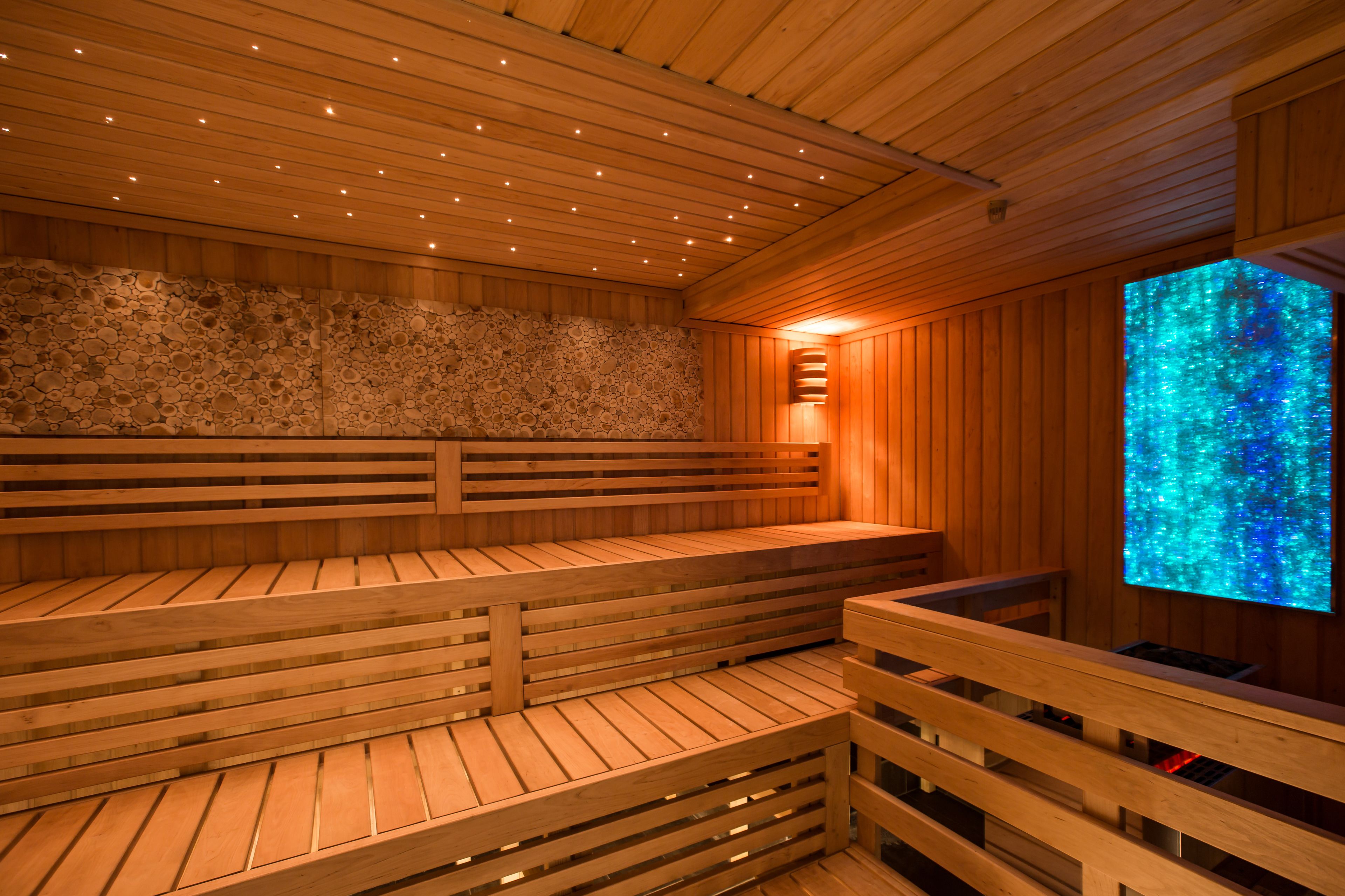 Un sauna avec des bancs en bois et un mur en pierre.