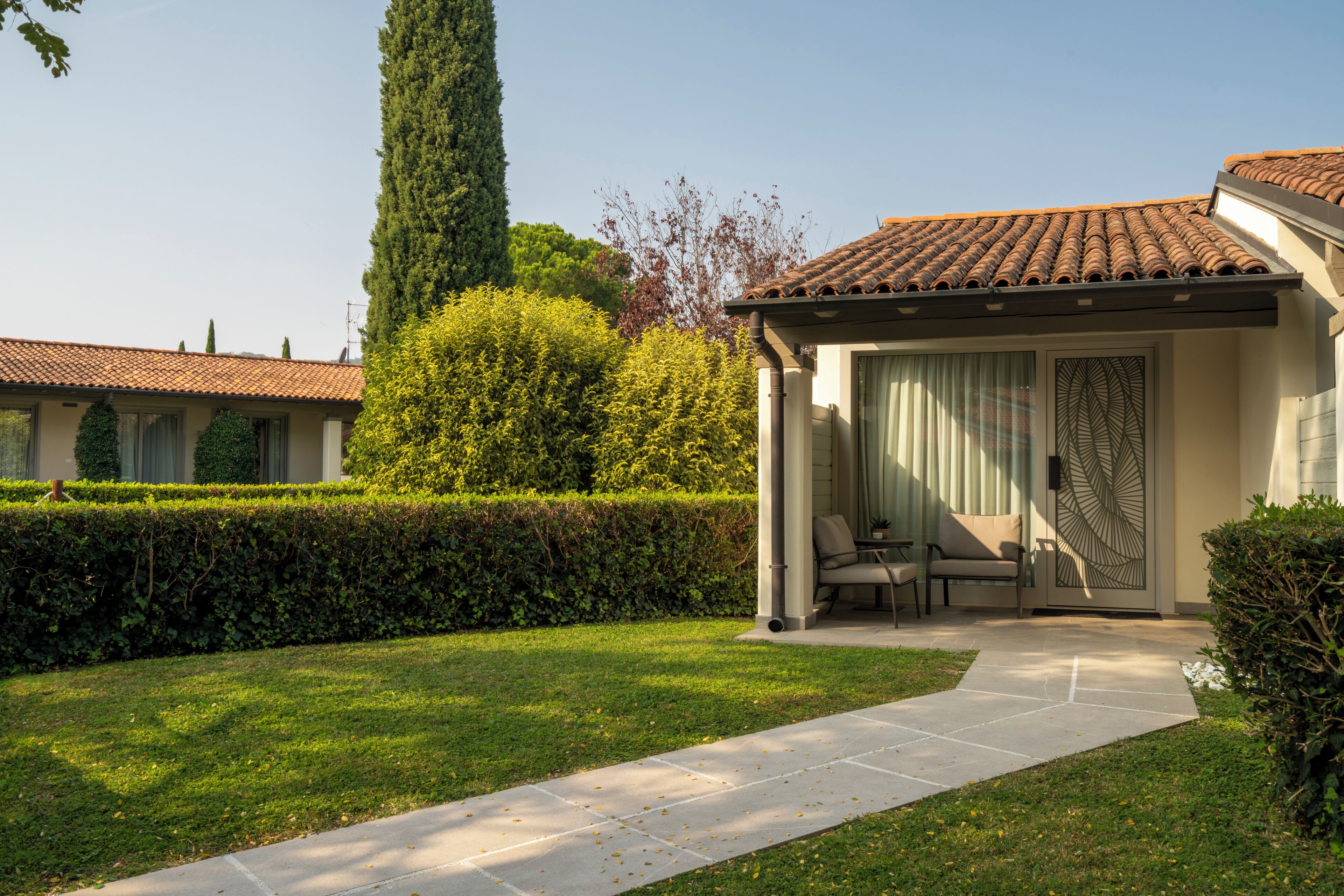 A house with a covered patio, a lawn, and a tall tree.