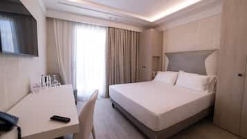Habitació d'hotel amb llit, escriptori, cadira, televisió de pantalla plana i nevera.