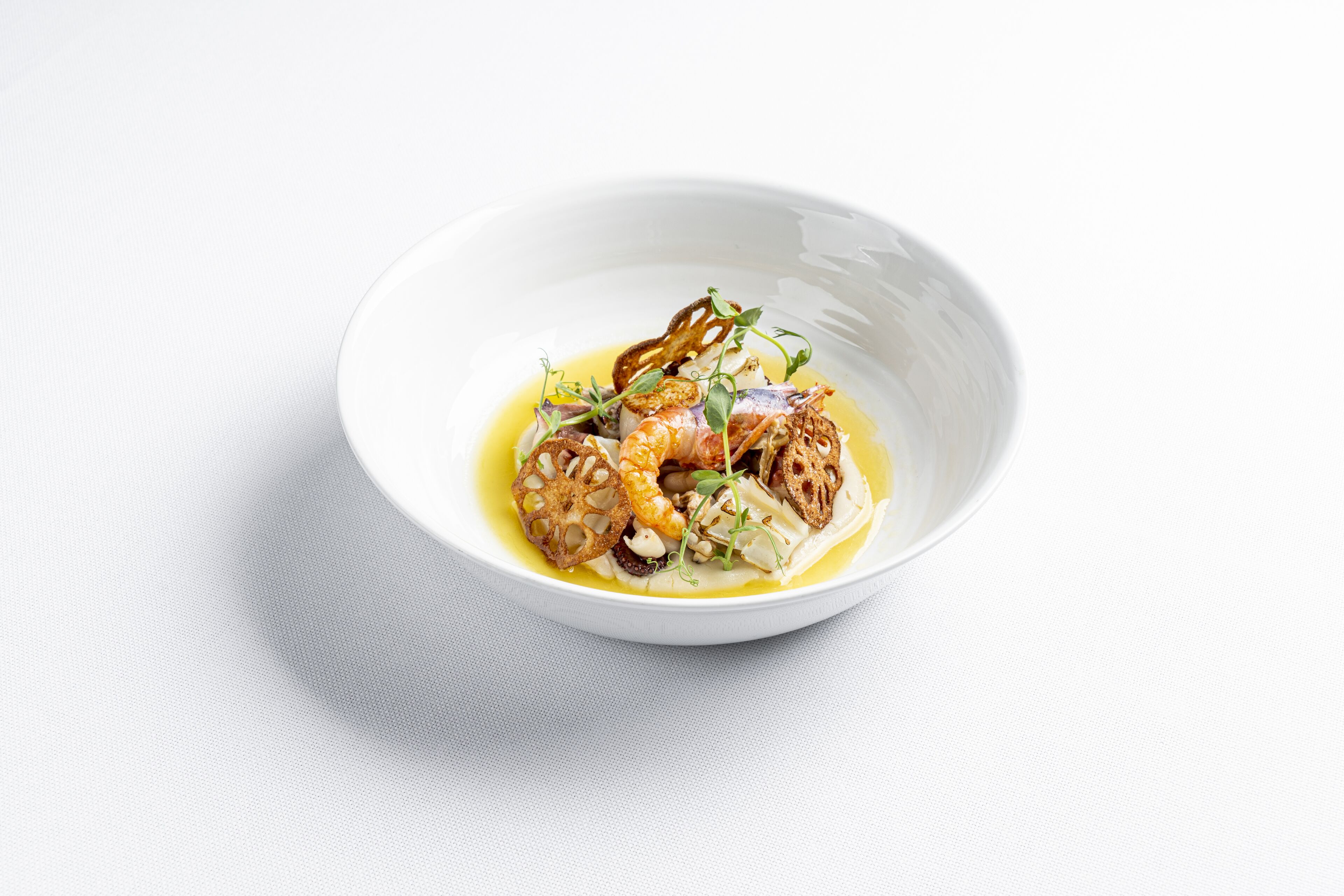 Un tazón blanco con un plato de mariscos, pan y hierbas.