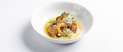 Un tazón blanco con un plato de mariscos, pan y hierbas.