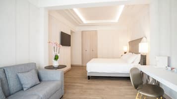 Una habitación de hotel moderna con un sofá gris, una cama, un escritorio y una silla.