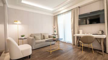 Ein modernes Wohnzimmer mit einer Couch, einem runden Tisch, einem Sessel, einem Fernseher und einem Schreibtisch.