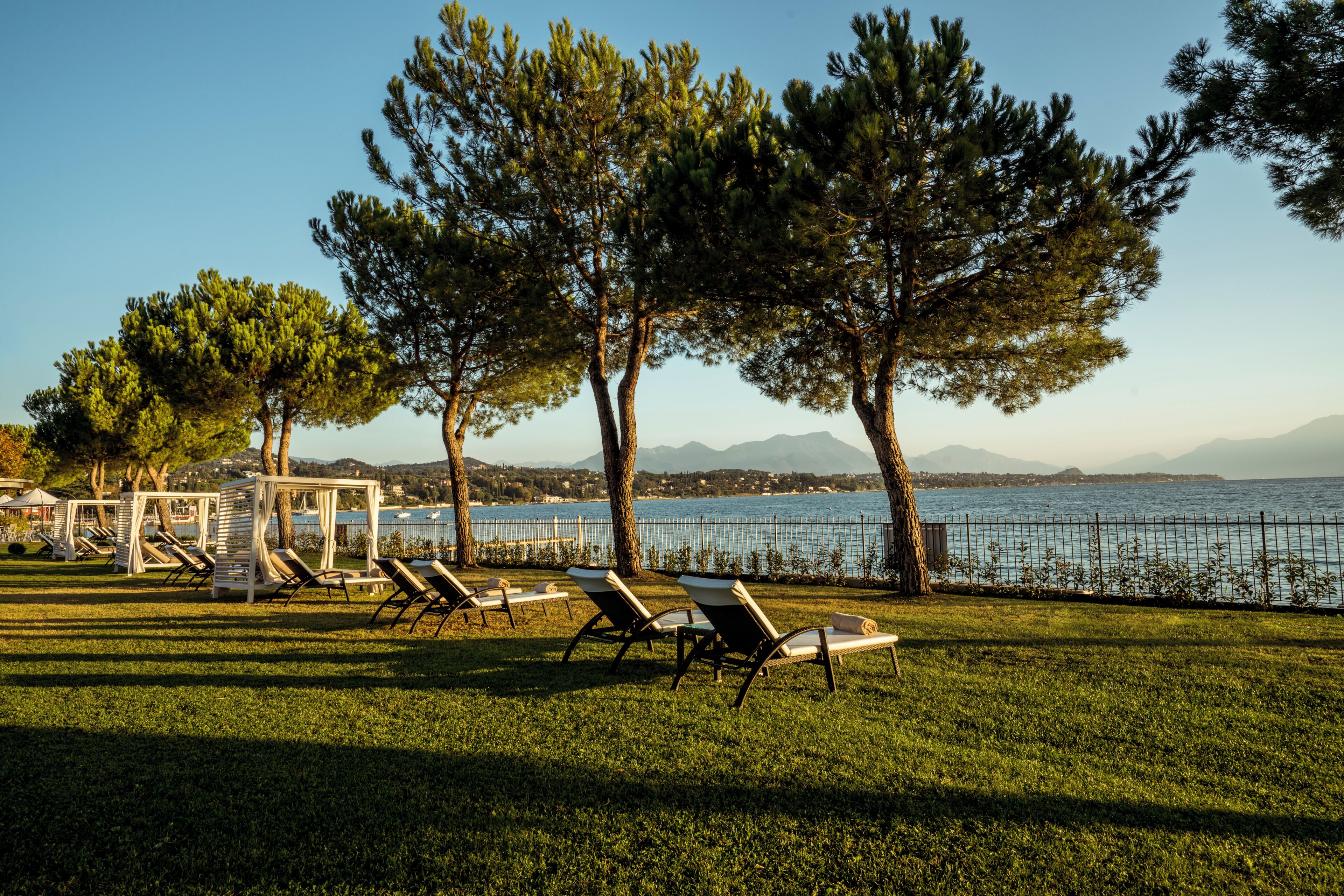 Een gazon met lounge stoelen en uitzicht op een waterpartij en bergen.