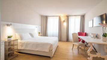 Habitación de hotel con cama, escritorio, silla, televisor y planta.