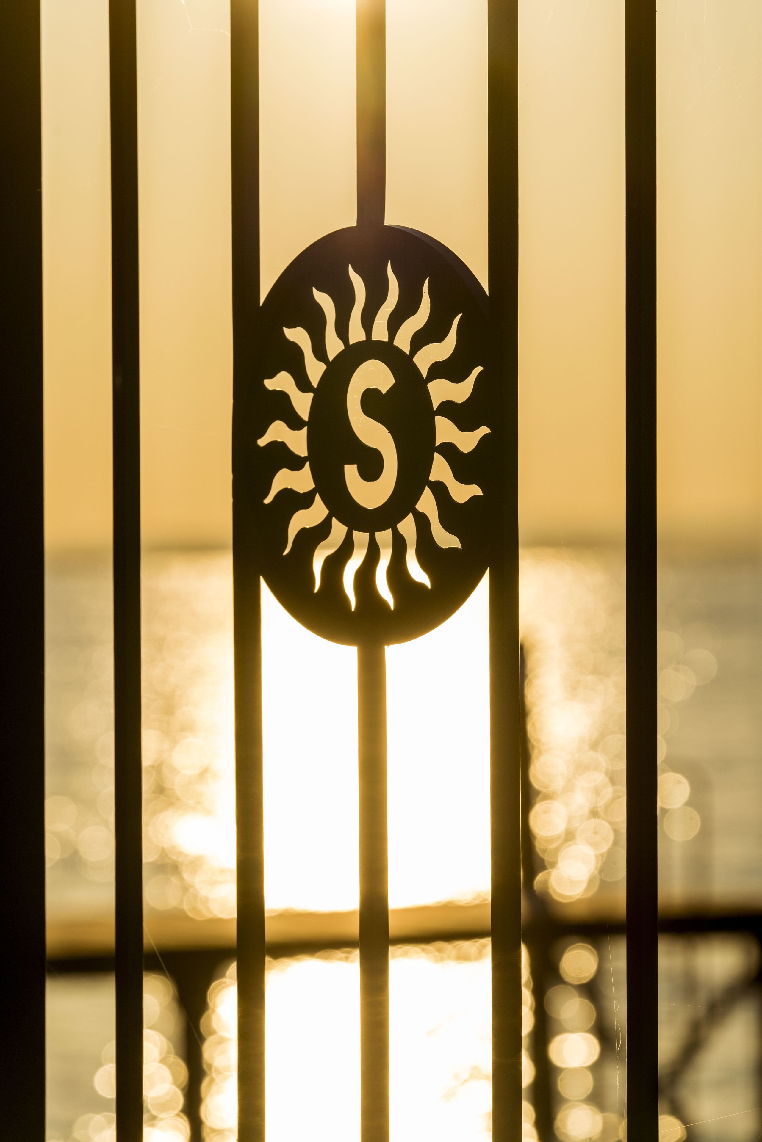 Un símbolo de sol con rayos, sobre un fondo difuminado de líneas verticales y una superficie reflectante.