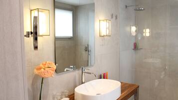 Un bagno moderno con un grande specchio, un lavandino bianco e una doccia.