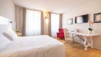 A hotel room with a bed, a desk, a chair, a TV, and curtains.