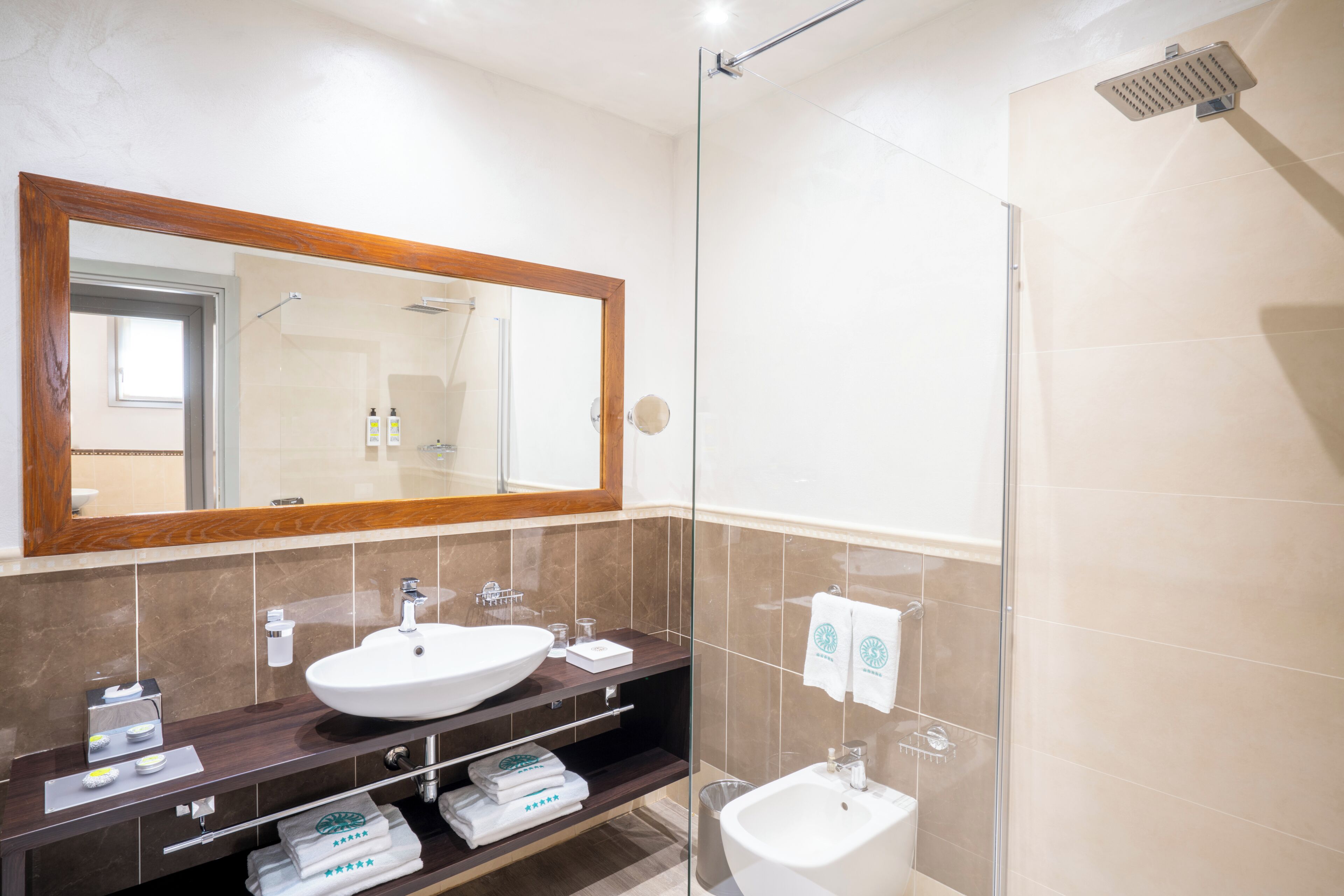 Une salle de bain moderne avec un grand miroir, un lavabo, une douche et un meuble-lavabo avec des articles de toilette.